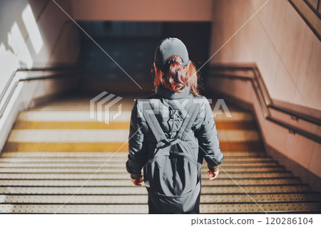Back view of a woman descending the stairs at a station 120286104