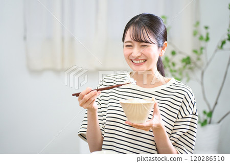 Young woman eating rice 120286510