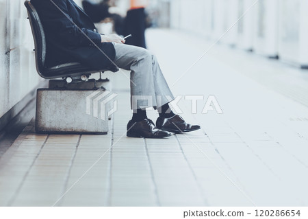 Legs of a man sitting on a chair 120286654