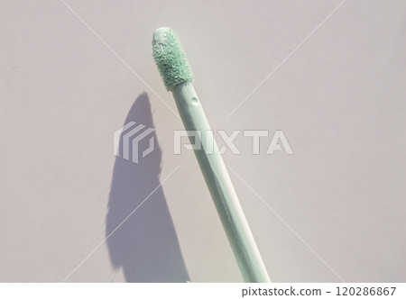 Close-up of a brush of green concealer for correcting skin imperfections, on a white background 120286867