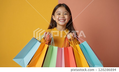 A happy Asian female girl holds colorful shopping bags in her hands, standing on a yellow background studio shot, A happy Asian female girl holds colorful shopping bags in her hands, standing on a yellow background studio shot, 120286894