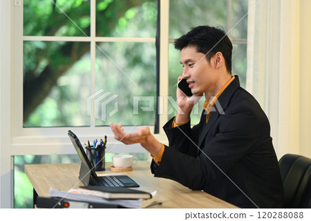 Professional businessman discussing business on phone and using digital tablet in modern office Professional businessman discussing business on phone and using digital tablet in modern office 120288088