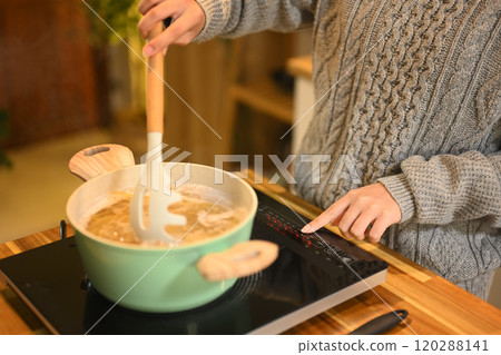 Young woman in sweaters cooking spaghetti in a cozy kitchen. People, food and domestic life concept Young woman in sweaters cooking spaghetti in a cozy kitchen. People, food and domestic life concept 120288141