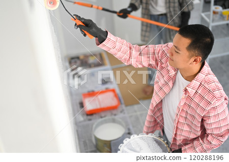 Two men collaborating, painting a wall in home improvement 120288196