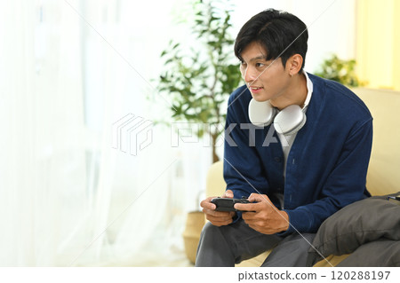 Man in casual outfit Playing video games with controller in living room Man in casual outfit Playing video games with controller in living room 120288197