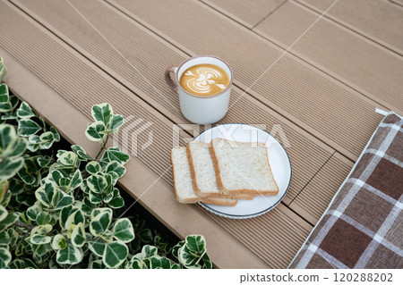 Plate of toast and a cup of coffee on a wooden terrace 120288202