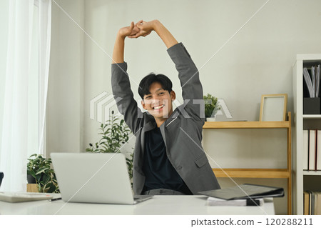 Relaxed office worker stretching after work session in the workplace Relaxed office worker stretching after work session in the workplace 120288211