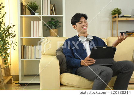 Cheerful asian man having an online video chat on digital tablet at home 120288214