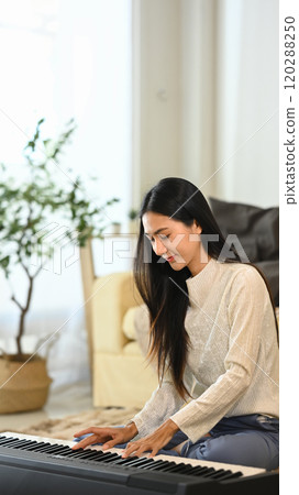 Young beautiful woman playing electric piano in living room 120288250