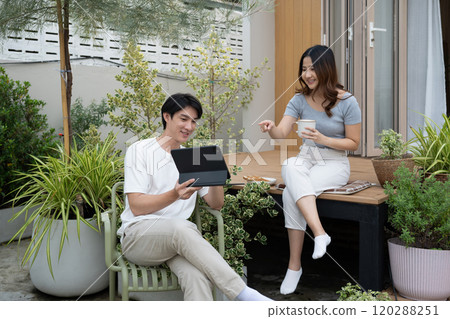 Relaxed millennial couple enjoying morning conversation and beverages in the backyard Relaxed millennial couple enjoying morning conversation and beverages in the backyard 120288251
