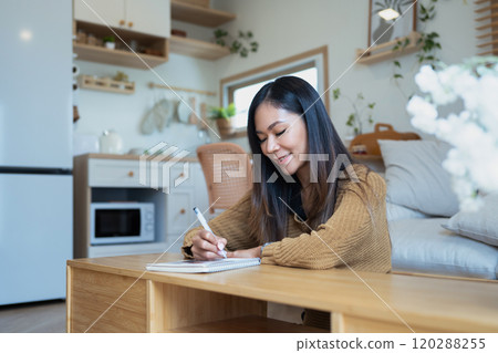 Attractive young woman taking notes with a smile in minimalist room Attractive young woman taking notes with a smile in minimalist room 120288255