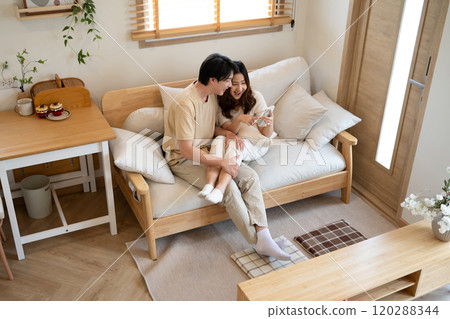 Happy millennial Asian couple using a smart phone together on sofa at home 120288344