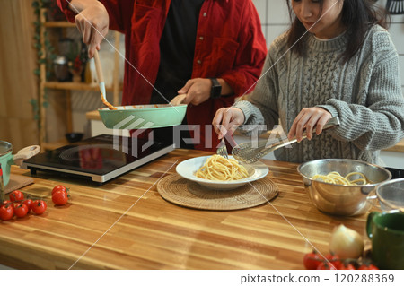 Happy couple preparing a delicious pasta dish for festive dinner Happy couple preparing a delicious pasta dish for festive dinner 120288369