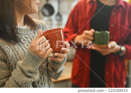 Relaxed young couple enjoying warm drinks together in kitchen 120288415