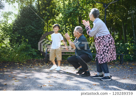 An elderly couple and their grandchildren playing in a large garden 120289359