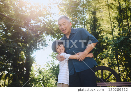 Smiling grandson and grandfather hugging each other 120289512
