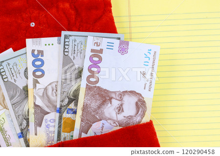Ukrainian banknotes are visible in bright red pouch placed next to yellow lined paper denominations include 1000 and 500 currency hryvnias notes 120290458
