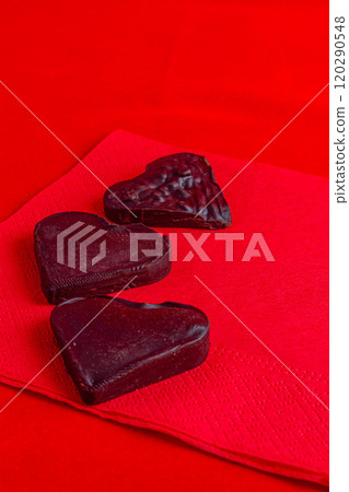 A heart made of dark chocolate on a red napkin on a red background A heart made of dark chocolate on a red napkin on a red background 120290548