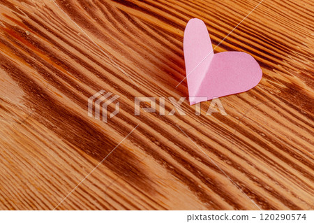 Pink heart cut out of paper on a wooden light background Pink heart cut out of paper on a wooden light background 120290574
