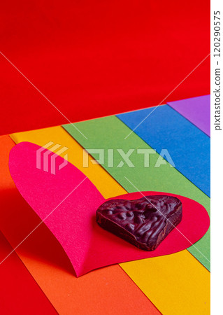 lgbt concept, chocolate heart on paper red on rainbow flag on red background 120290575