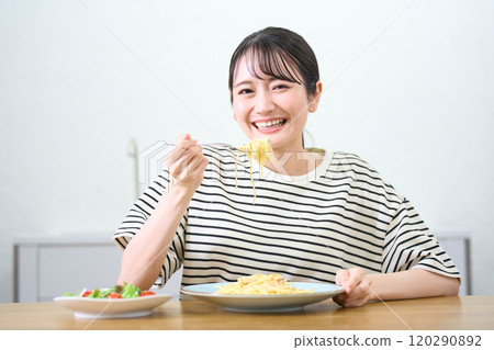 A young woman eating pasta A young woman eating pasta 120290892