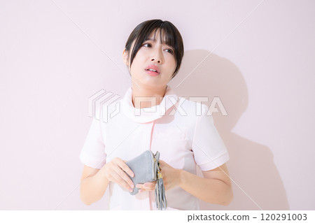 A female nurse is troubled because she is short of money and is looking at her wallet Pink background 120291003
