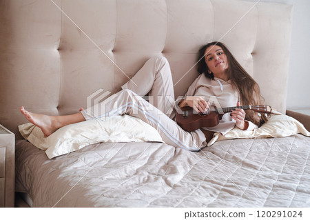 Beautiful woman playing ukulele, relaxed at home. Beautiful woman playing ukulele, relaxed at home. 120291024
