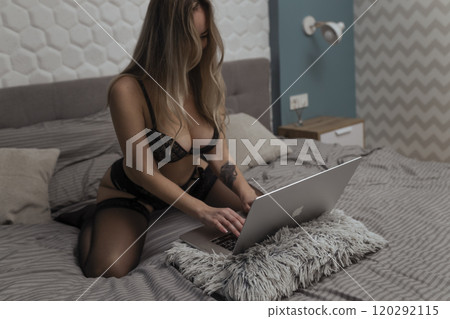 A beautiful, young girl shoots a webcam, works as a model. The concept of online flirting, sex on the Internet A beautiful, young girl shoots a webcam, works as a model. The concept of online flirting, sex on the Internet 120292115