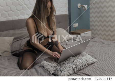 A beautiful, young girl shoots a webcam, works as a model. The concept of online flirting, sex on the Internet A beautiful, young girl shoots a webcam, works as a model. The concept of online flirting, sex on the Internet 120292116