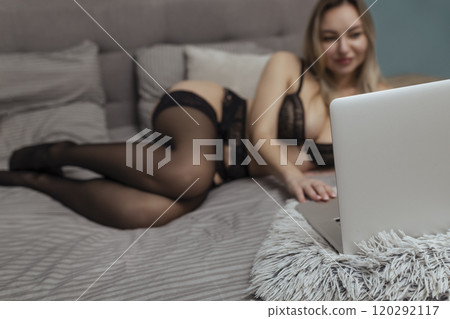 A beautiful, young girl shoots a webcam, works as a model. The concept of online flirting, sex on the Internet A beautiful, young girl shoots a webcam, works as a model. The concept of online flirting, sex on the Internet 120292117