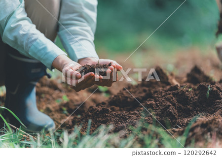 一個女人看著田裡的土壤 120292642