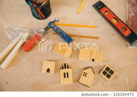 Wooden houses, pencils, and tools on a workbench. Perfect for home construction, DIY projects, and handmade woodwork. Carpentry tools for crafting at home workshop 120293473