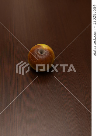 An apple affected by the disease, on a brown wooden surface. A sick spoiled apple in close-up. Fruit rot of fruit trees. One half of the apple looks healthy, the other half looks rotten An apple affected by the disease, on a brown wooden surface. A sick spoiled apple in close-up. Fruit rot of fruit trees. One half of the apple looks healthy, the other half looks rotten 120293584