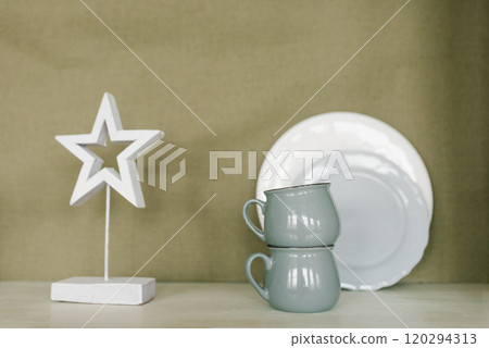 White star is on a shelf next to two cups and a white plate White star is on a shelf next to two cups and a white plate 120294313