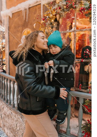 Young woman and a child stand on a balcony decorated for Christmas 120294319