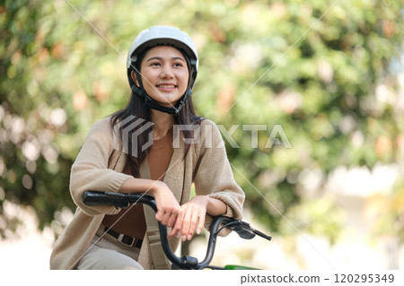 A woman is sitting on a bicycle wearing a helmet 120295349
