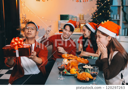 Group of young Asian man and women as friends having fun at a New Year's celebration, holding gift boxes standing by Christmas tree decoration, midnight countdown Party at home with holiday season. Group of young Asian man and women as friends having fun at a New Year's celebration, holding gift boxes standing by Christmas tree decoration, midnight countdown Party at home with holiday season. 120297263
