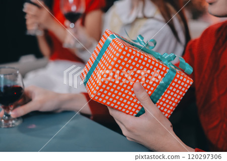 Friends opening Christmas gifts in living room 120297306