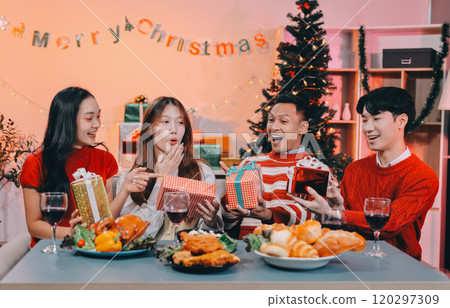 Friends opening Christmas gifts in living room Friends opening Christmas gifts in living room 120297309