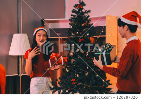 Group of happy Asian friends celebrating Christmas and decorate the Christmas tree indoors. Beauty woman with Christmas Gifts. New Year party. Woman hands decorate Christmas tree red ball, bauble. Group of happy Asian friends celebrating Christmas and decorate the Christmas tree indoors. Beauty woman with Christmas Gifts. New Year party. Woman hands decorate Christmas tree red ball, bauble. 120297320