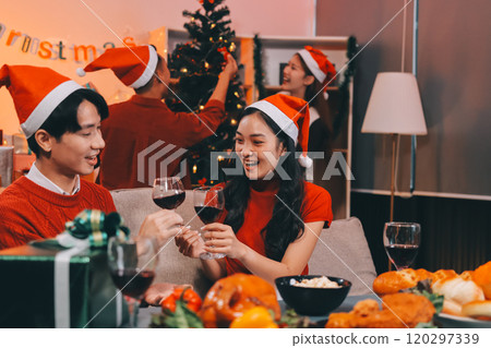 Group of young Asian man and women as friends having fun at a New Year's celebration, holding gift boxes standing by Christmas tree decoration, midnight countdown Party at home with holiday season. 120297339