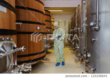 Winemaker working in modern large winery factory liquor drink industry quality. Staff inspecting wine in modern wine factory. Winery manufacturing quality control. Alcohol and wine winemaking process 120298641