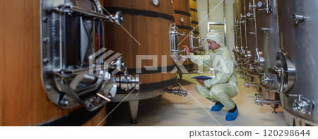 Winemaker working in modern large winery factory liquor drink industry quality. Staff inspecting wine in modern wine factory. Winery manufacturing quality control. Alcohol and wine winemaking process 120298644