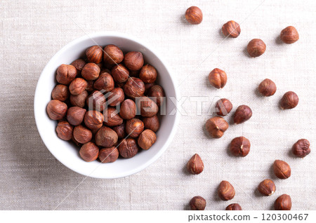 Hazelnut kernels, also known as cobnuts and filberts, in a white bowl on linen. Whole, dried and shelled nuts, fruits of the hazel tree Corylus avellana. Ready to eat as snack, and to use for baking. Hazelnut kernels, also known as cobnuts and filberts, in a white bowl on linen. Whole, dried and shelled nuts, fruits of the hazel tree Corylus avellana. Ready to eat as snack, and to use for baking. 120300467
