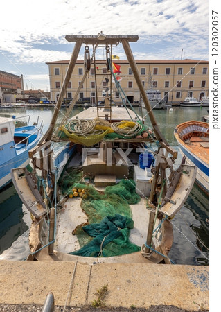 View of a fishing boat with nets and equipment docked in Livorno harbor on a sunny day 120302057