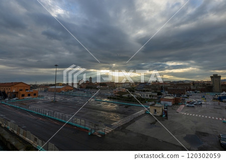 Morning scene at Livorno harbor with ferry at sunrise cloudy sky and sun rays reflecting on water Morning scene at Livorno harbor with ferry at sunrise cloudy sky and sun rays reflecting on water 120302059