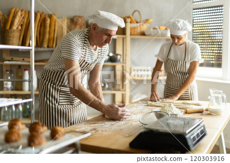 Elderly man and woman kneading and rolling out dough Elderly man and woman kneading and rolling out dough 120303916