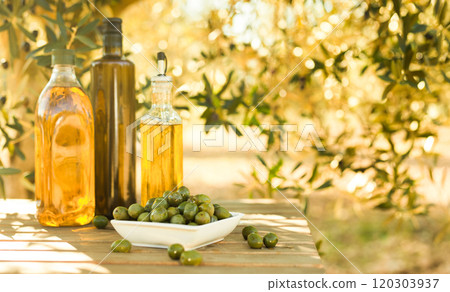 Green olives and oil on table in olive grove 120303937