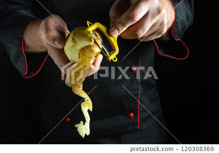 Under the soft glow of kitchen lights, a chef adeptly peels a potato, showcasing culinary technique. The elegant motion reveals fresh, golden skin spiraling away, evoking a sense of artistry Under the soft glow of kitchen lights, a chef adeptly peels a potato, showcasing culinary technique. The elegant motion reveals fresh, golden skin spiraling away, evoking a sense of artistry 120308369