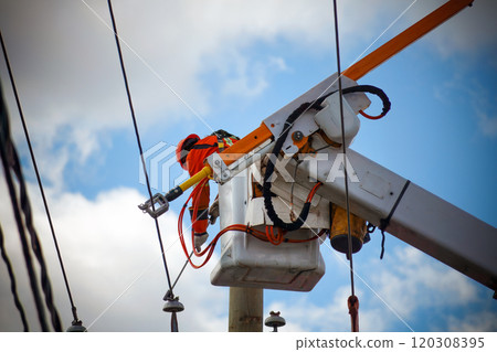 Electricity Line Worker Conducting Repairs on Power Lines from an Aerial Platform 120308395